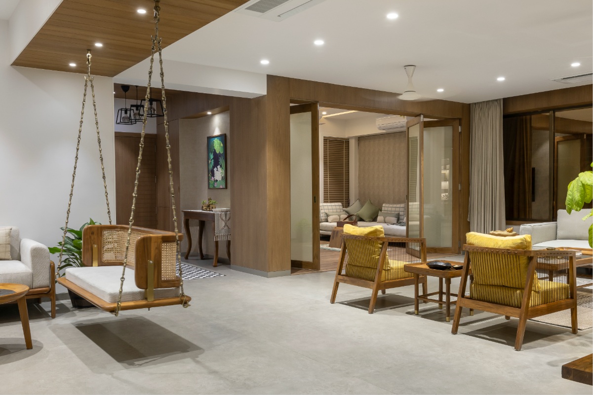 Surat apartment living room — jhula in foreground, yellow cane chairs, view to mandir
