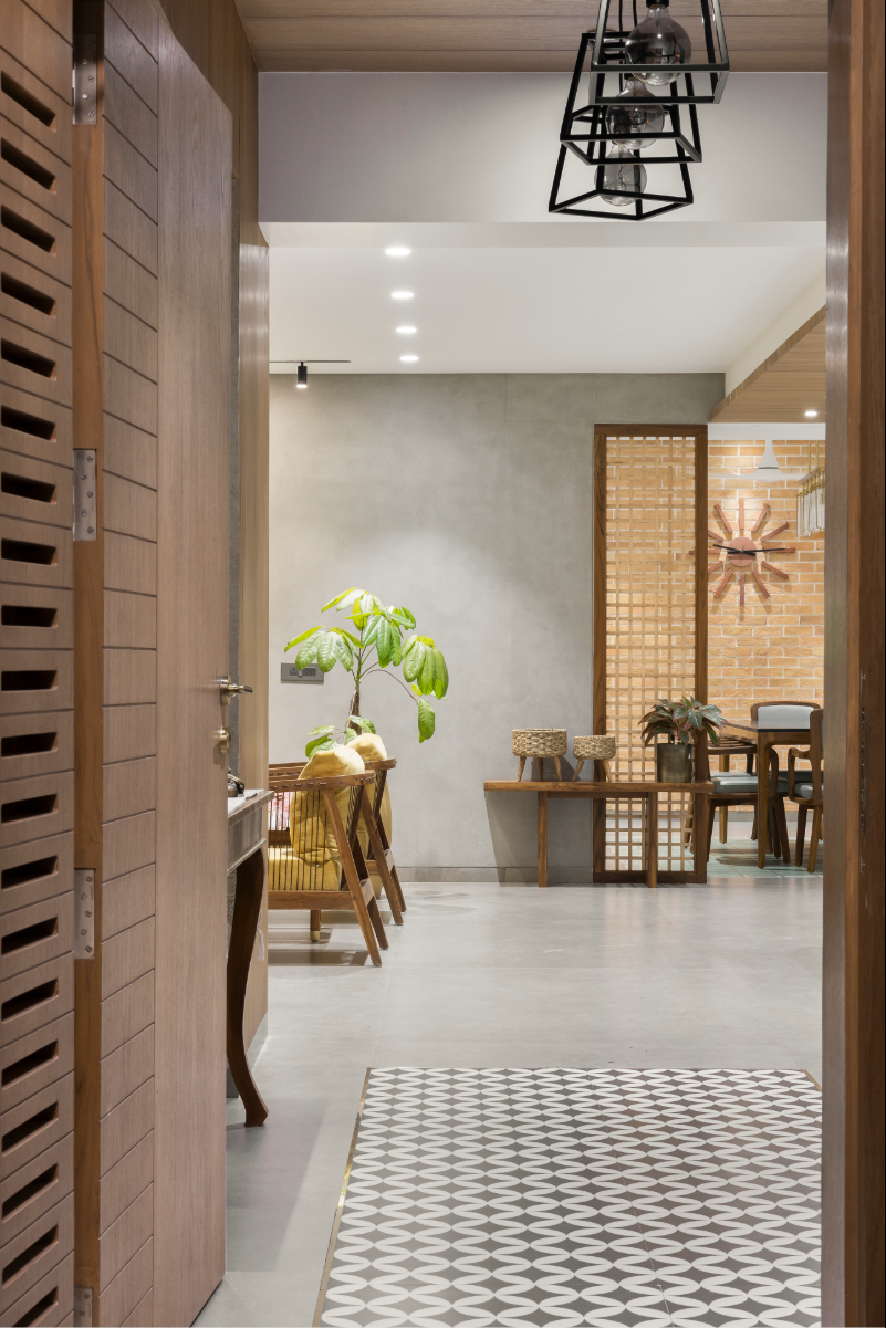 The entry foyer — patterned cement tile at the threshold, timber-clad walls, a console with a Buddha figure and botanical painting