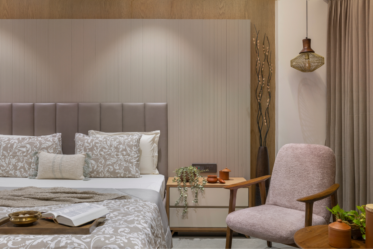 The parents' bedroom — fluted grey headboard panel, mauve upholstered armchair, warm timber cabinetry, pendant light