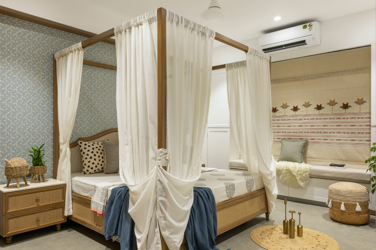 The daughter's bedroom — four-poster timber bed with white drapes, blue floral wallpaper, folk-motif wall panel with a day bed