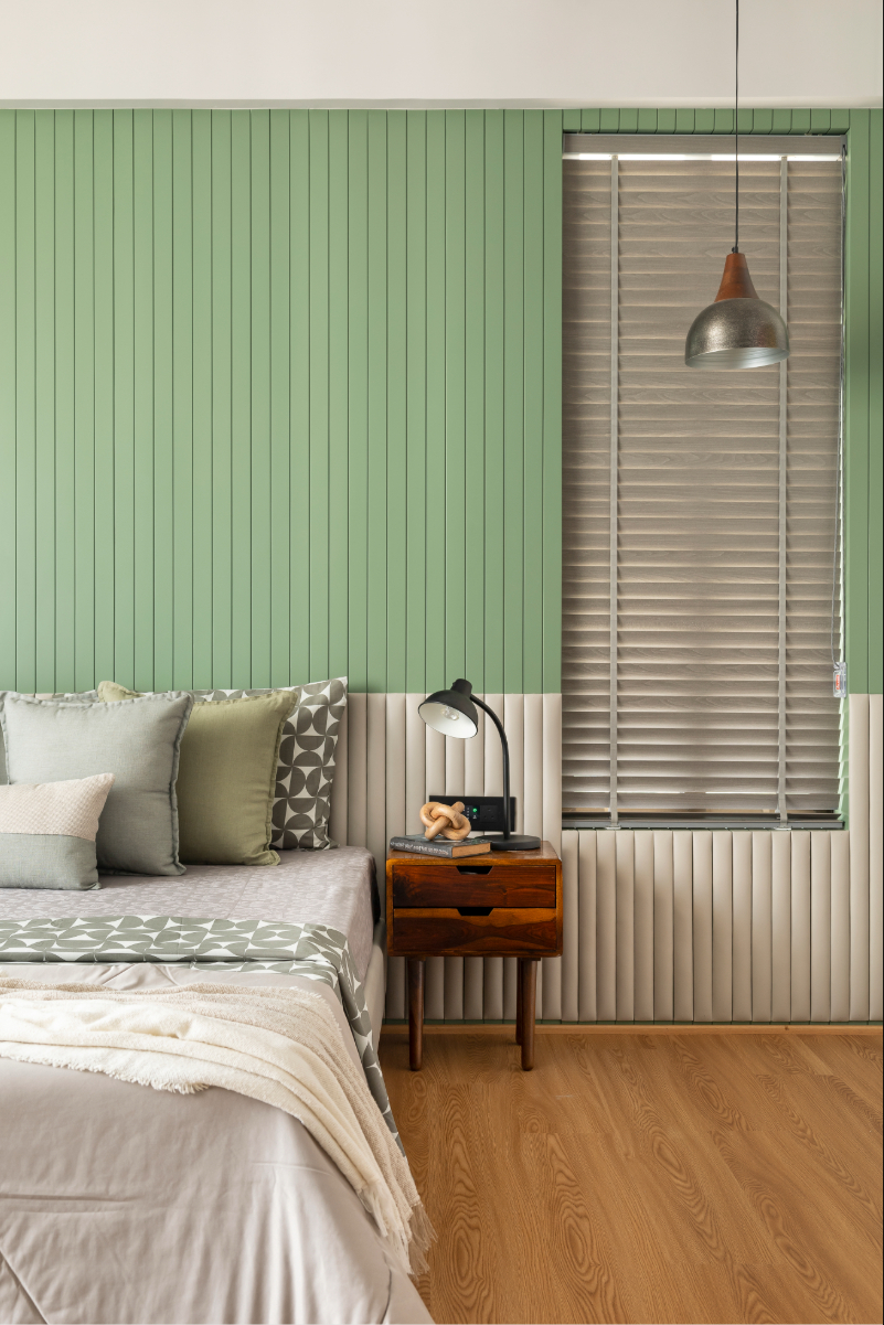 The son's bedroom — sage-green fluted headboard wall, dark timber nightstand, wood-look floor, pop-art prints on the far wall with a keyboard
