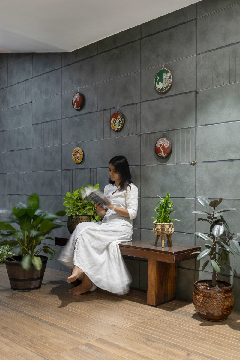 The balcony of a Surat apartment — dark green textured walls, folk art medallions, potted plants