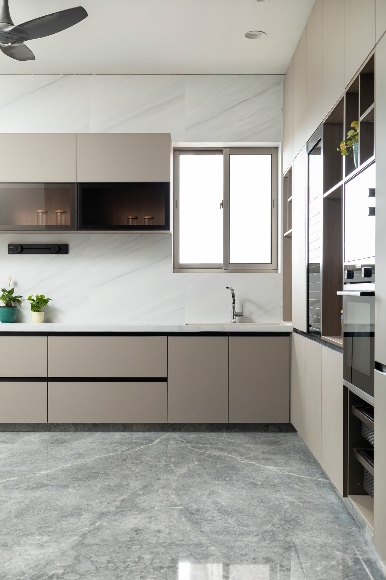 The kitchen — handle-less mushroom-grey cabinetry, marble splashback, grey marble flooring, integrated appliances