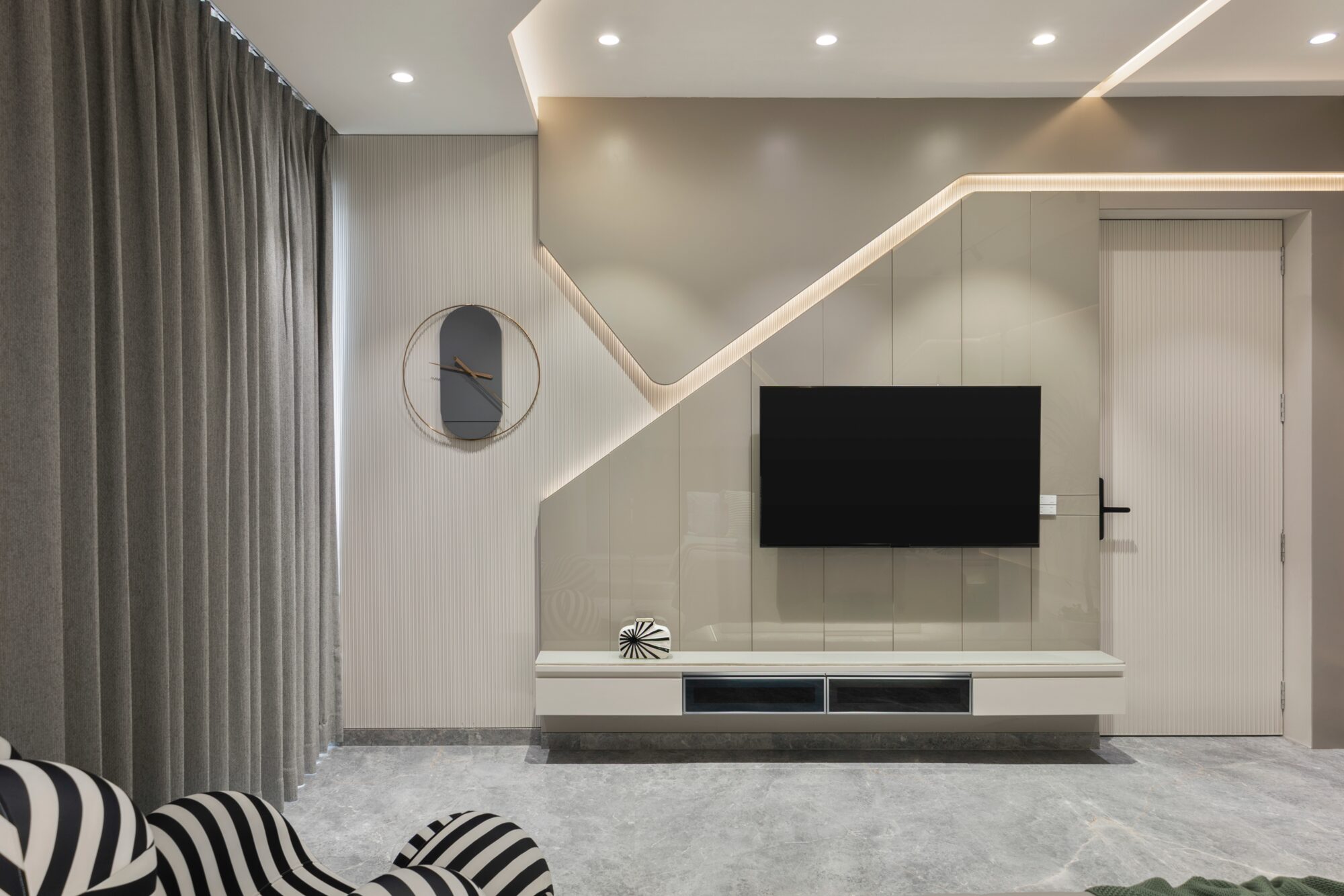 The same bedroom — view of the TV wall opposite the bed, with the integrated TV unit and clock