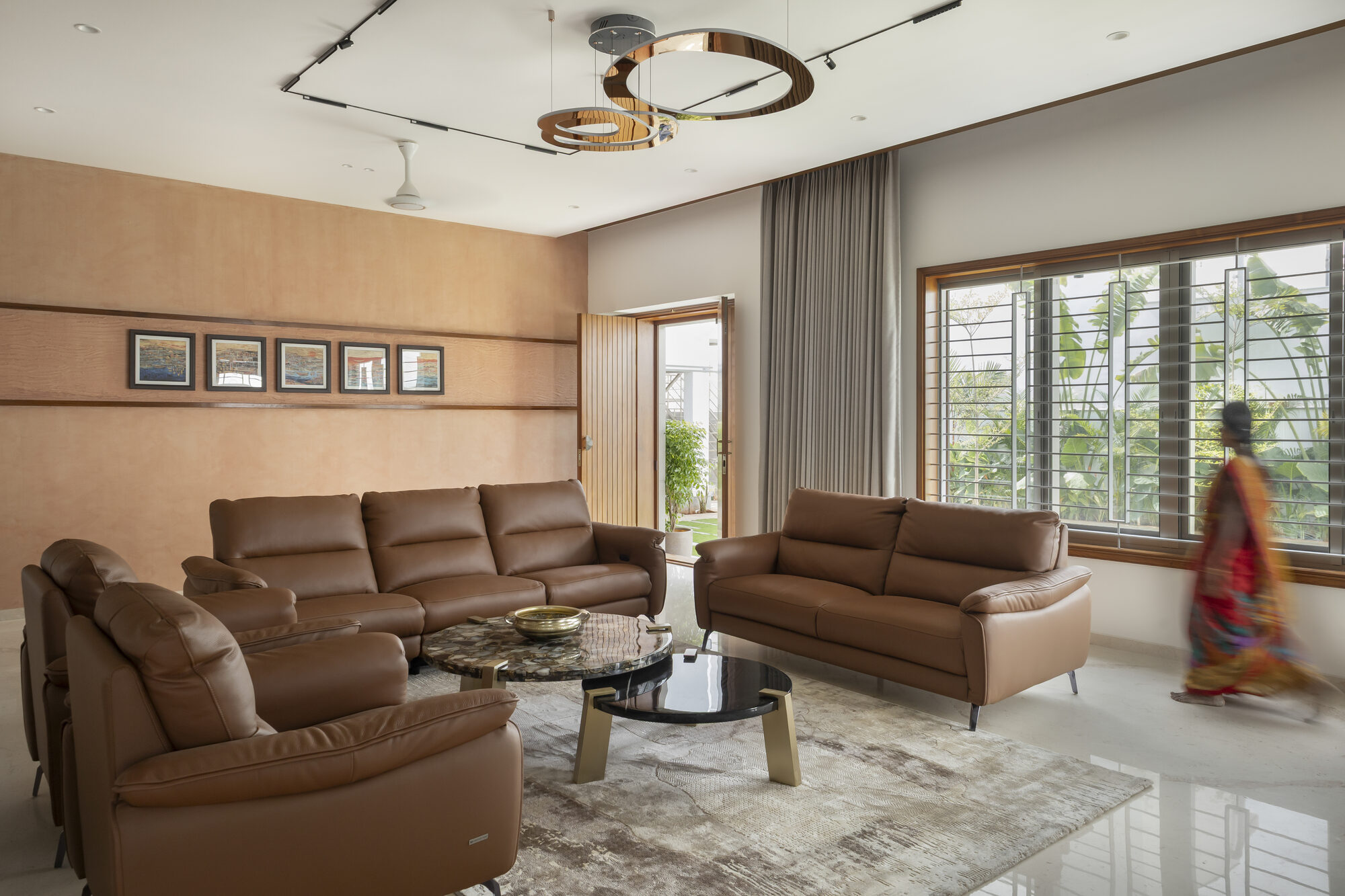 Living room with terracotta lime-plaster wall, tan leather seating, and tall windows opening to the garden
