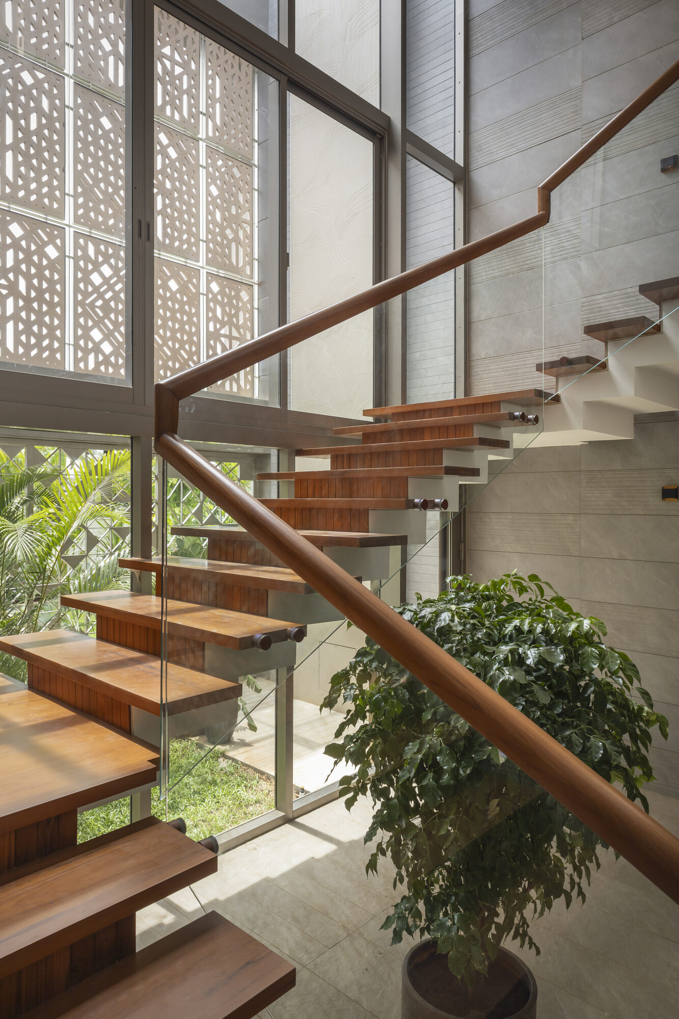 Floating timber staircase against a perforated jali screen, designed by 4th Dimension