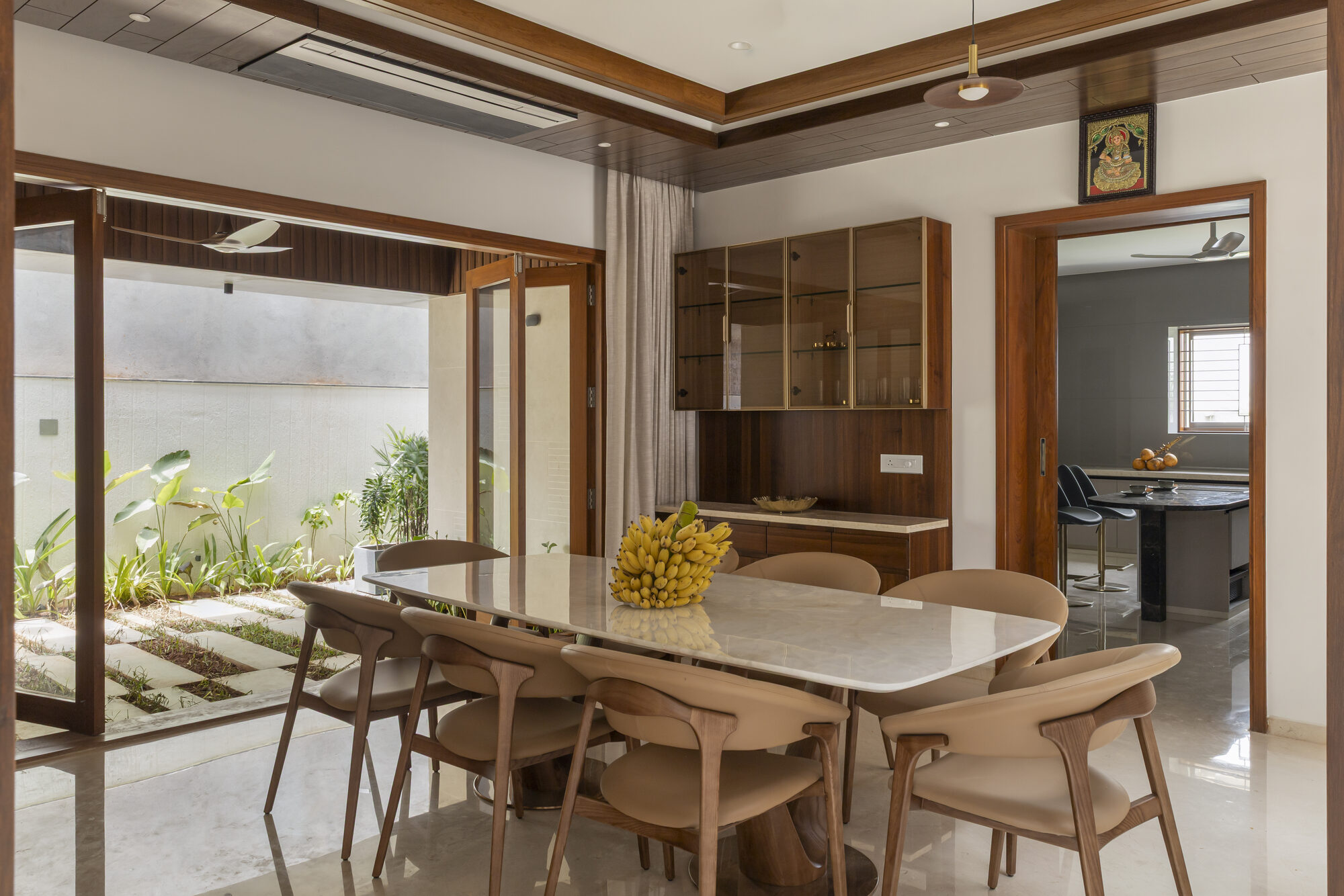 Dining room with the side door open onto a private green court — stone paths set into grass