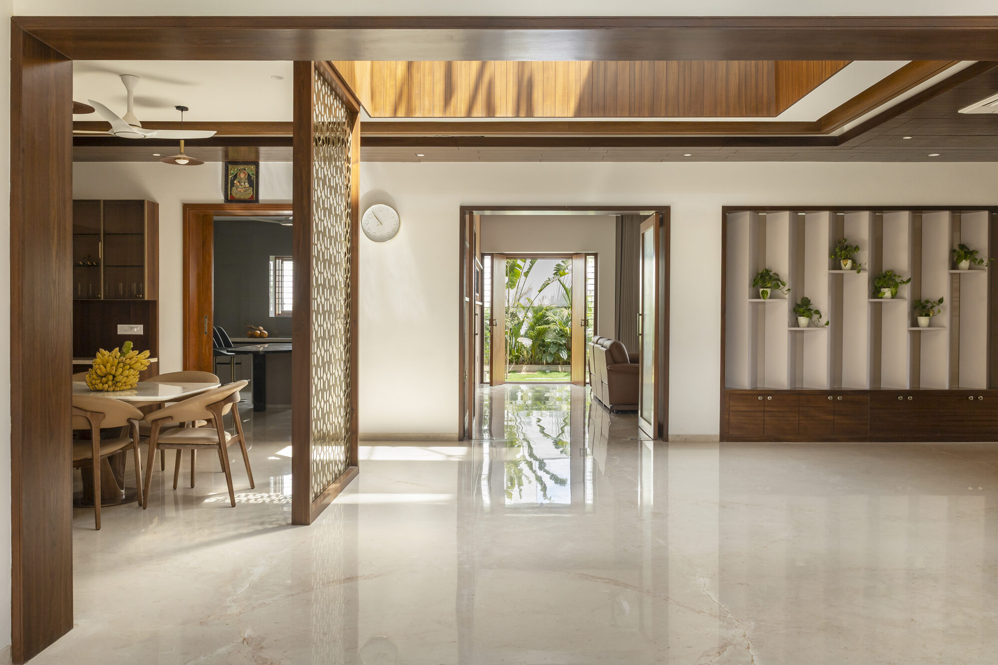 Interior view: a single sightline runs from the family area, through a doorway, past a brass jali screen, through the entrance, to the garden beyond